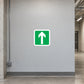 Left Arrow Sticker applied in warehouse straight emergency escape corridor, smooth light grey wall, clear onward passage glimpsed at edge