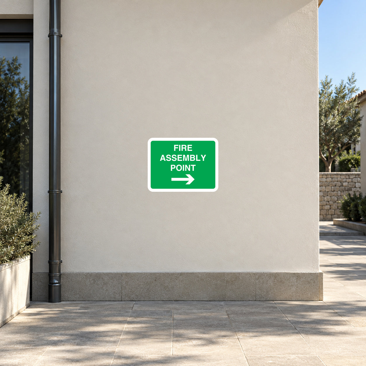 Fire assembly point wayfinding sticker with green label, text, and right arrow