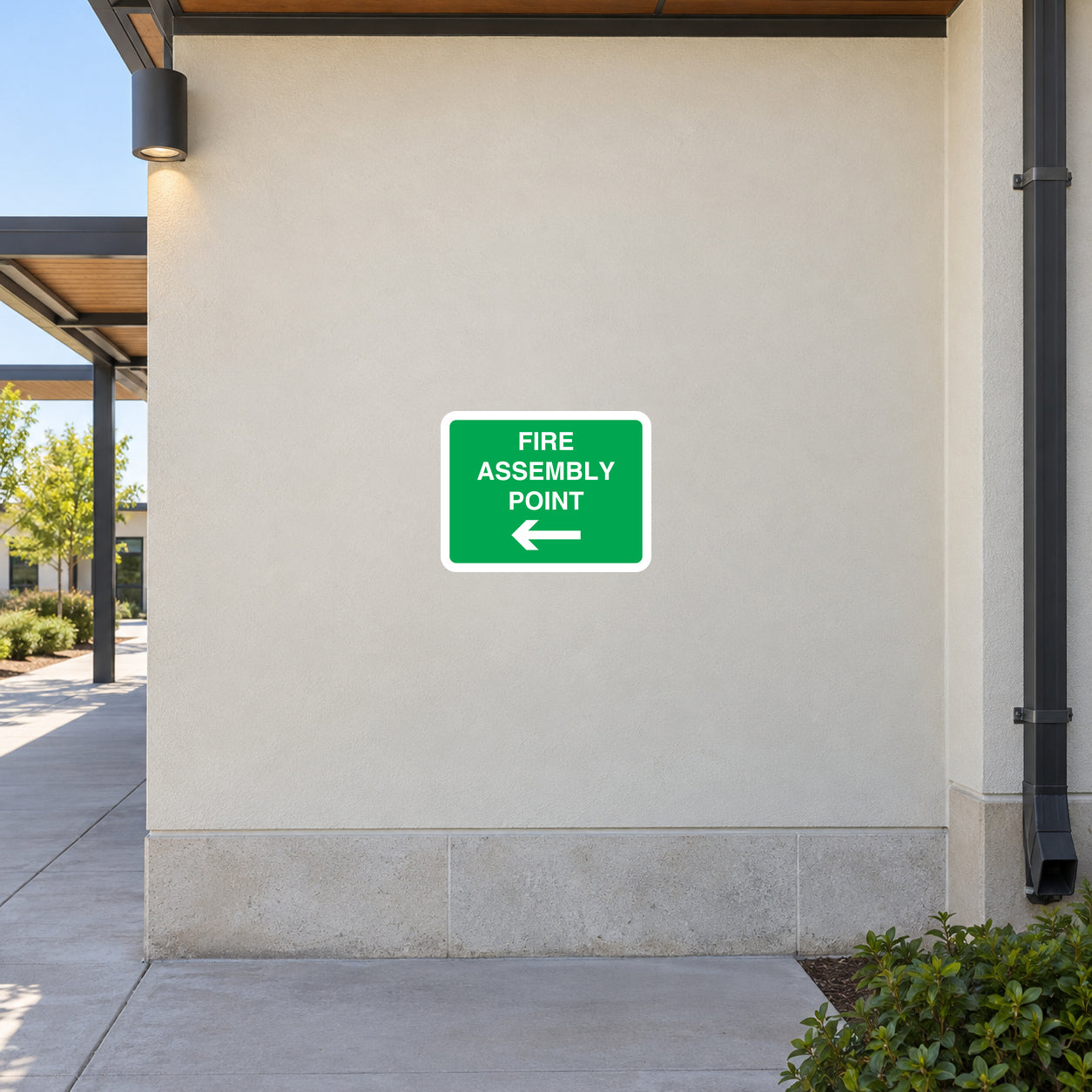 Green fire assembly point sign sticker with arrows pointing left and down