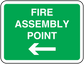 Fire assembly point sticker, green sign with white text and left-pointing arrow