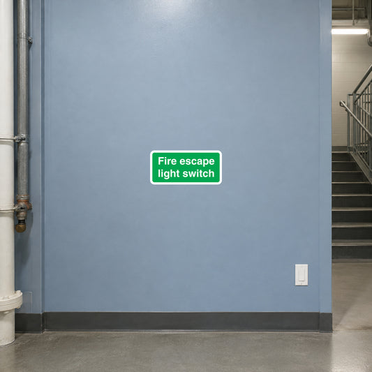 Fire escape light switch sticker with green label text on wall near a light switch