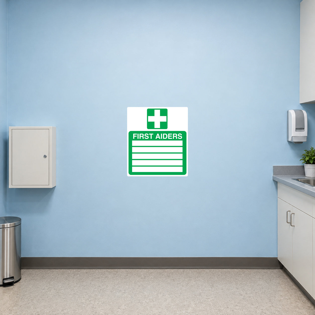 Emergency First Aiders Sticker applied in Blank smooth pale blue wall in a commercial printing first aid corner, small unmarked medical cabinet below y80%, sink at far right, linoleum flooring.