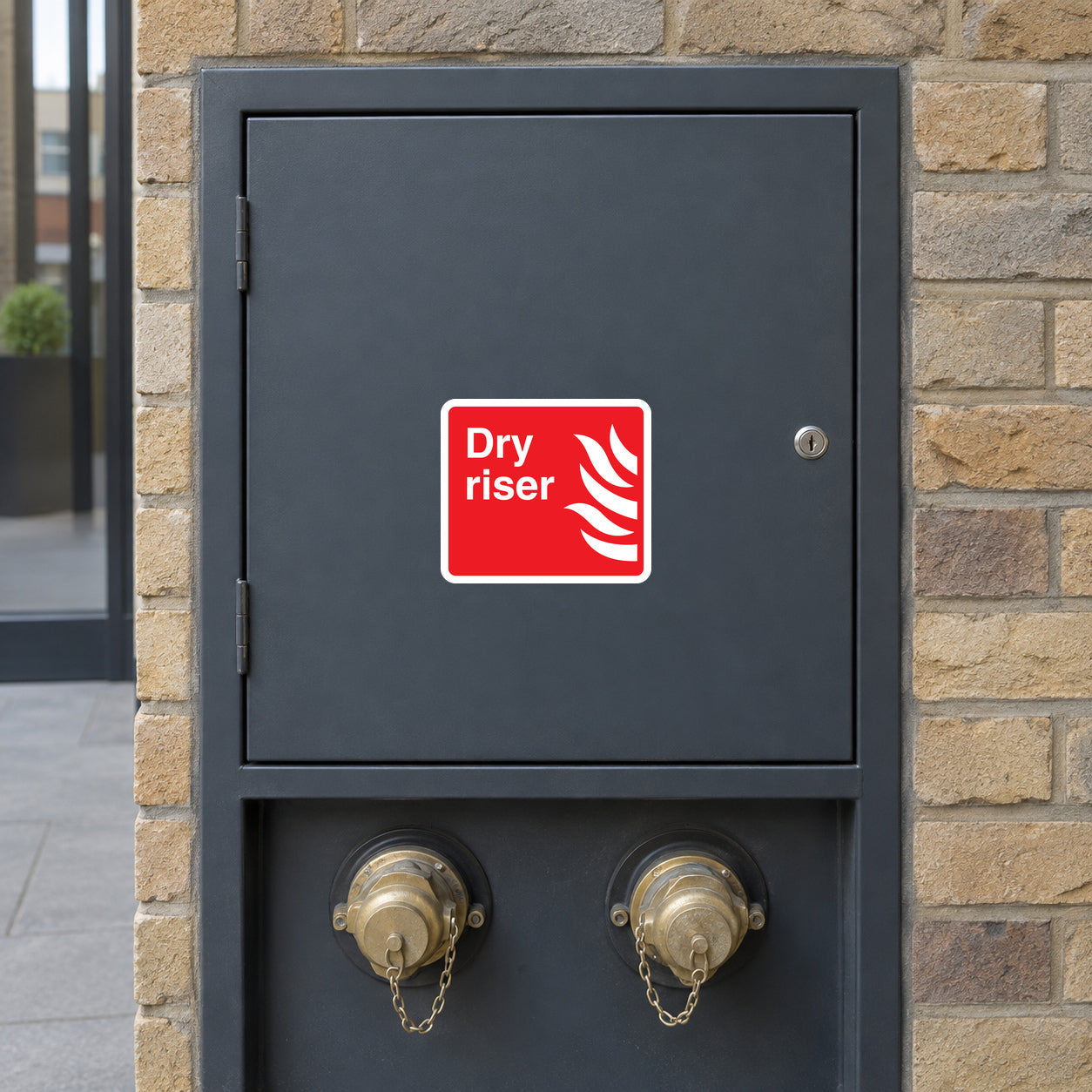 Dry riser fire sticker on dark metal panel, red label with white hand icon and text