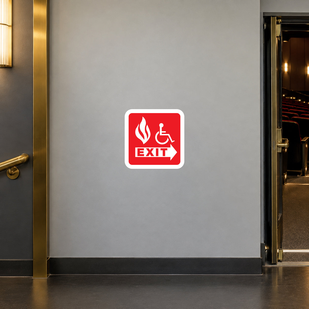 Handicap Fire Exit Sticker applied in a theatre accessible escape corridor, smooth pale gray wall, a wide level wheelchair-accessible exit doorway at far RIGHT, no steps, flat dark vinyl floor, brass door trim left