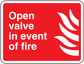 Red fire safety sticker with white text 'Open valve in event of fire' and flame icon.