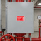 Red and white sprinkler control valve sticker on gray metal access panel