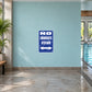 No Swimsuits After Dark Fun Sign Sticker applied to a pale aqua indoor pool wall