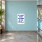 White square sign sticker with blue and black text: It's Not Rude to Swim in the Nude