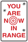Fun sign sticker: red target text 'YOU ARE NOW IN RANGE'