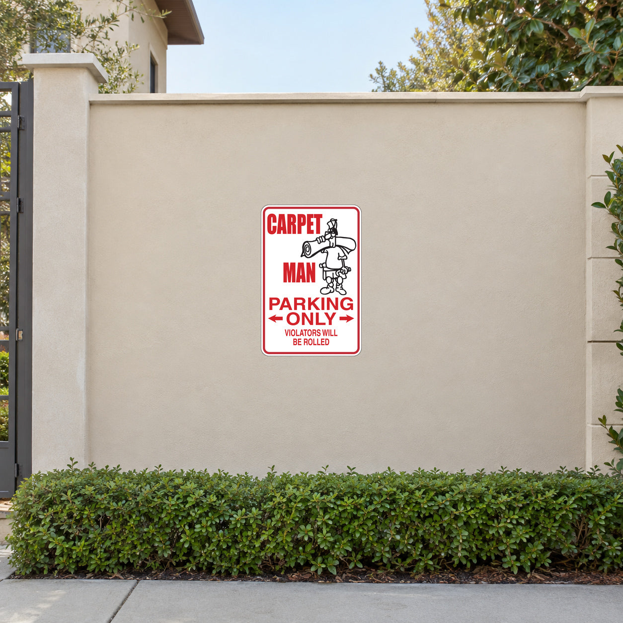 Carpet Man Parking Only Sticker applied to a beige garden boundary wall