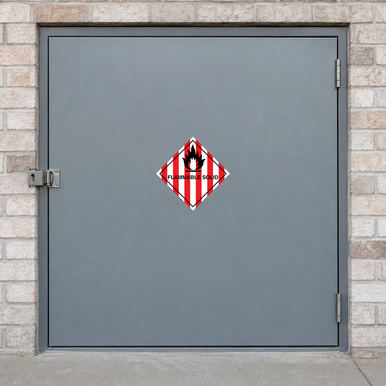 Hazardous Safety Sign Sticker applied in a specialized materials store with pale brick outer walls, smooth grey SINGLE-door steel cabinet front, latch at extreme left