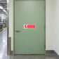 NO Safety Sign Sticker applied in factory packaging staff entrance, solid pale green access door, production corridor glimpsed extreme left