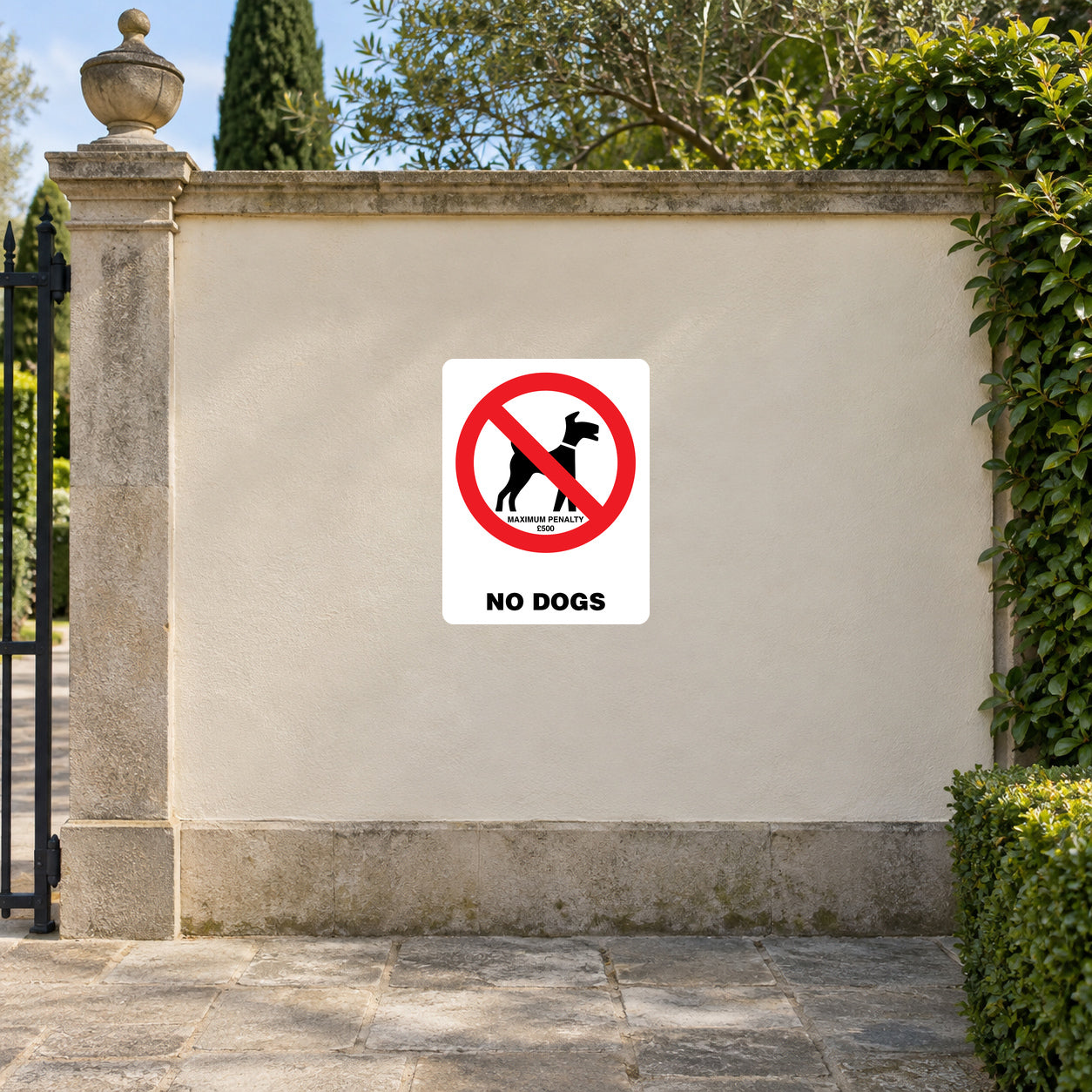 NO Dogs Sign Sticker applied in a cream rendered wall at a municipal garden entrance, stone paving and hedge edges
