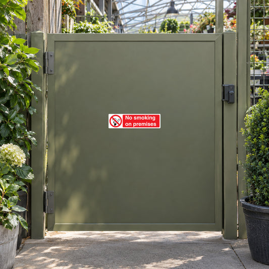 NO Smoking Sign Sticker applied in flat olive service gate at a garden center, plants outside edges