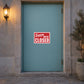 Business Open Closed Sign Sticker applied in a closed tailoring studio entrance, smooth solid pale turquoise door, stone threshold and potted tree at far right, quiet dusk