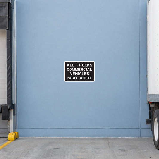Road sign sticker with black border, reads: ALL TRUCKS COMMERCIAL VEHICLES NEXT RIGHT