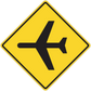 Road sign sticker: yellow diamond with black directional arrows.