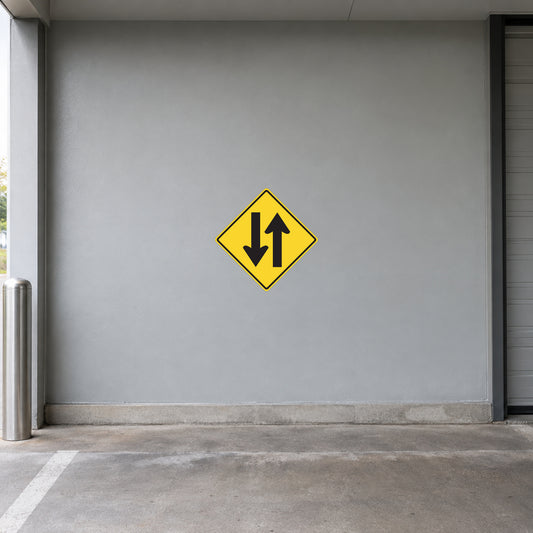 Yellow road sign sticker with black double-arrow down and up in a diamond