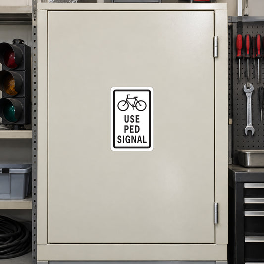 Road sign sticker with bike icon and 'USE PED SIGNAL' text
