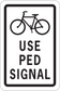Road sign sticker with bicycle icon and bold text "USE PED SIGNAL"