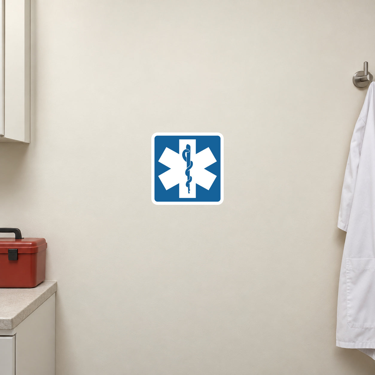 Road Sign Sticker applied in An ivory first aid training room wall beside closed medical kit low left and empty coat hook far right, smooth blank center