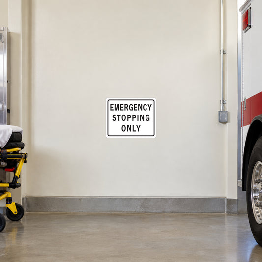Road Sign Sticker applied in A pale cream emergency vehicle bay wall with trolley far left and ambulance wheel edge far right, smooth blank center