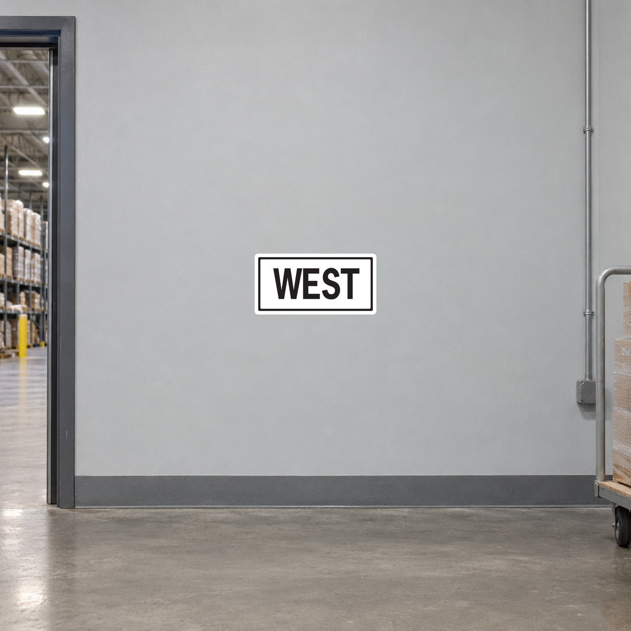 Road Sign Sticker applied in A light grey warehouse wayfinding corridor wall with pallet cart at extreme right and doorway far left, blank smooth center