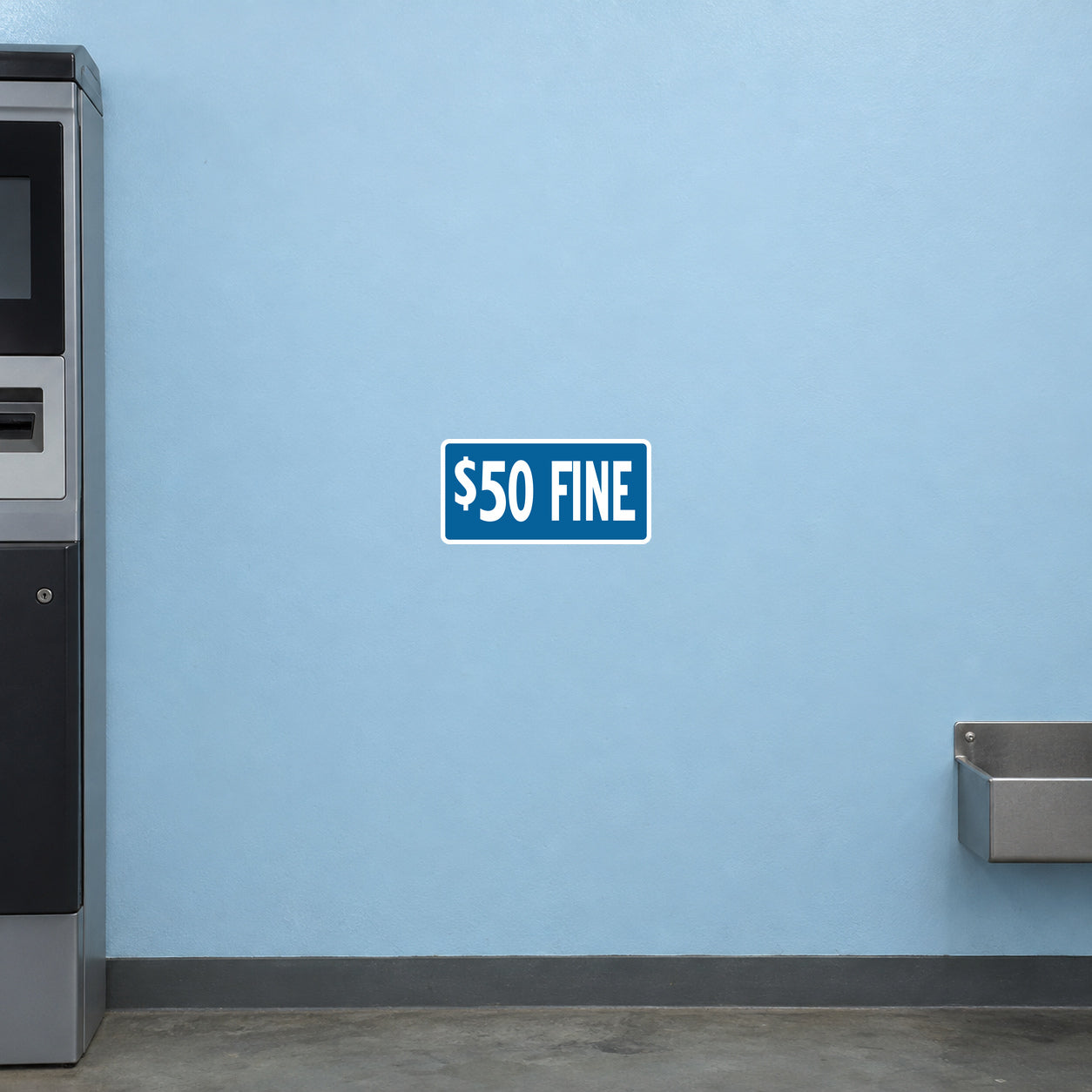 Road Sign Sticker applied in A pale blue parking office wall with ticket machine extreme left and coin tray low right, blank smooth center