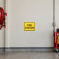 Road Sign Sticker applied in A cream fire station vehicle bay wall with red hose coil far left and equipment trolley low right, blank smooth center