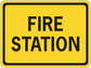 Road sign sticker with yellow background and black border, text "FIRE STATION".