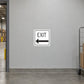 Road Sign Sticker applied in A light grey warehouse exit corridor smooth wall with doorway at extreme left and parcel trolley far right, blank central surface