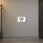 Road Sign Sticker applied in A warm grey workshop corridor smooth wall with empty coat rack extreme left and door edge right, blank center