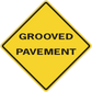 Road sign sticker with yellow diamond and text “GROOVED PAVEMENT”
