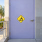 Road Sign Sticker applied in An accessible community center entrance, smooth pale lavender metal service door, wheelchair ramp edge at extreme left, brushed handle far right, soft morning sun