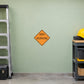 Road Sign Sticker applied in A contractor tool storage room, uninterrupted pale green wall, folded ladder far left and hardhat far right