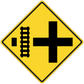 Yellow road sign sticker with black cross and vertical measurement marks
