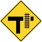 Yellow road sign sticker with black T and rail-crossing symbol