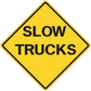 Yellow road sign sticker: diamond SLOW TRUCKS warning text, black border