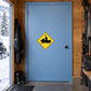 Road Sign Sticker applied in A snowmobile lodge equipment room, smooth light blue door, ski gear far right and snowy doorway glimpse far left