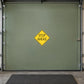 Road Sign Sticker applied in A private driver training garage, smooth dusty sage metal door, handle extreme right and floor mat below