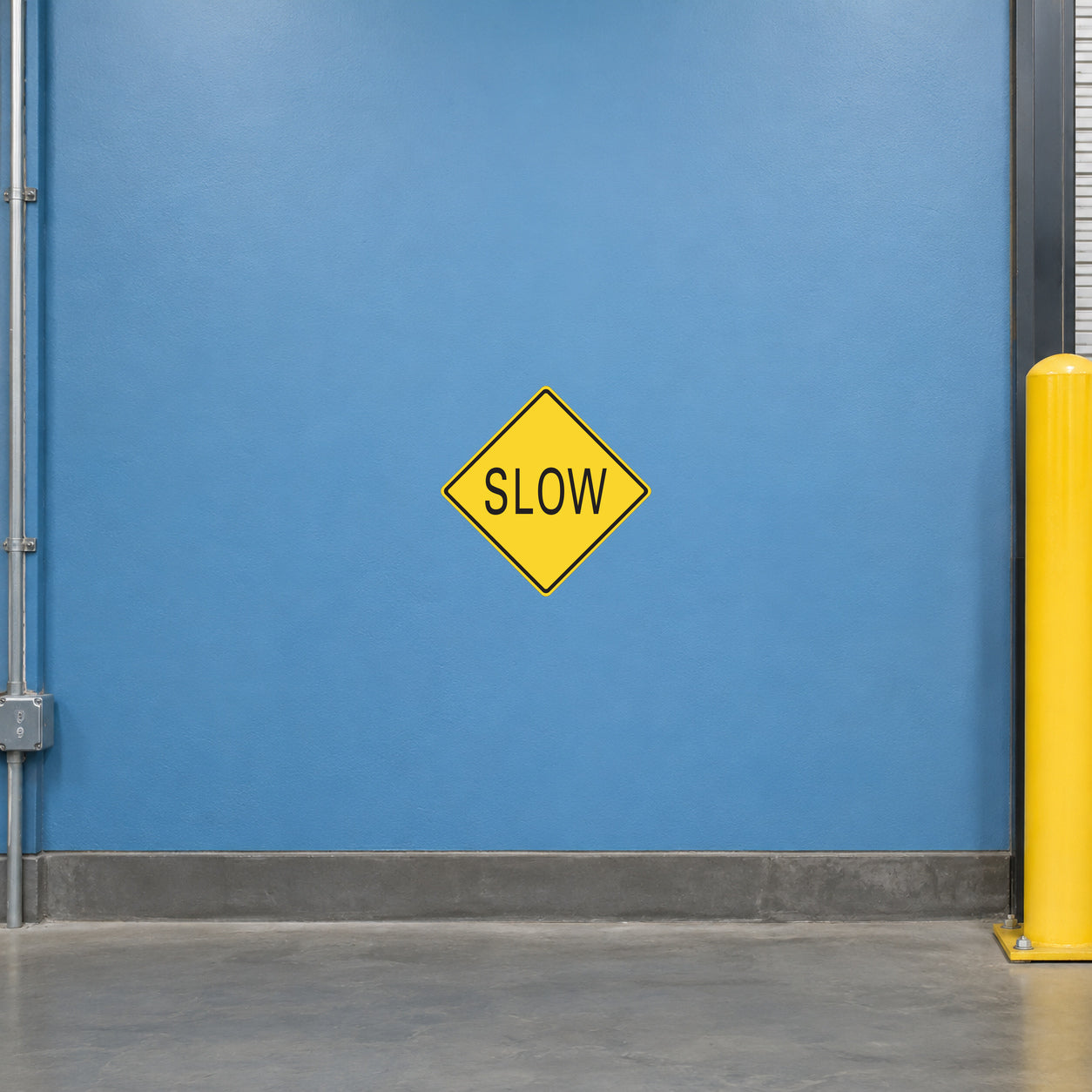 Road Sign Sticker applied in A warehouse vehicle access corridor, uninterrupted soft blue painted wall, yellow guard post extreme right
