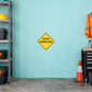 Road Sign Sticker applied in A roadworks equipment garage, uninterrupted pale aqua wall, folded orange vest far right