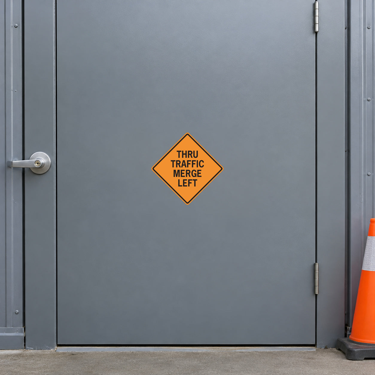 Road Sign Sticker applied in A public works traffic store, smooth slate grey steel door, handle far left and orange cone far right