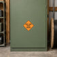 Road Sign Sticker applied in A rural contractor equipment room, smooth muted green cabinet front, cable spool far right