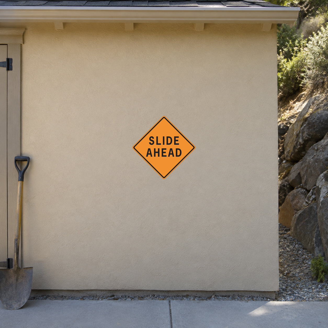 Orange diamond road sign sticker with black text “SLIDE AHEAD”