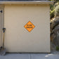 Orange diamond road sign sticker with black text “SLIDE AHEAD”