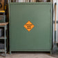 Road Sign Sticker applied in A road shoulder maintenance workshop, smooth dusty green steel cabinet door, rake extreme right
