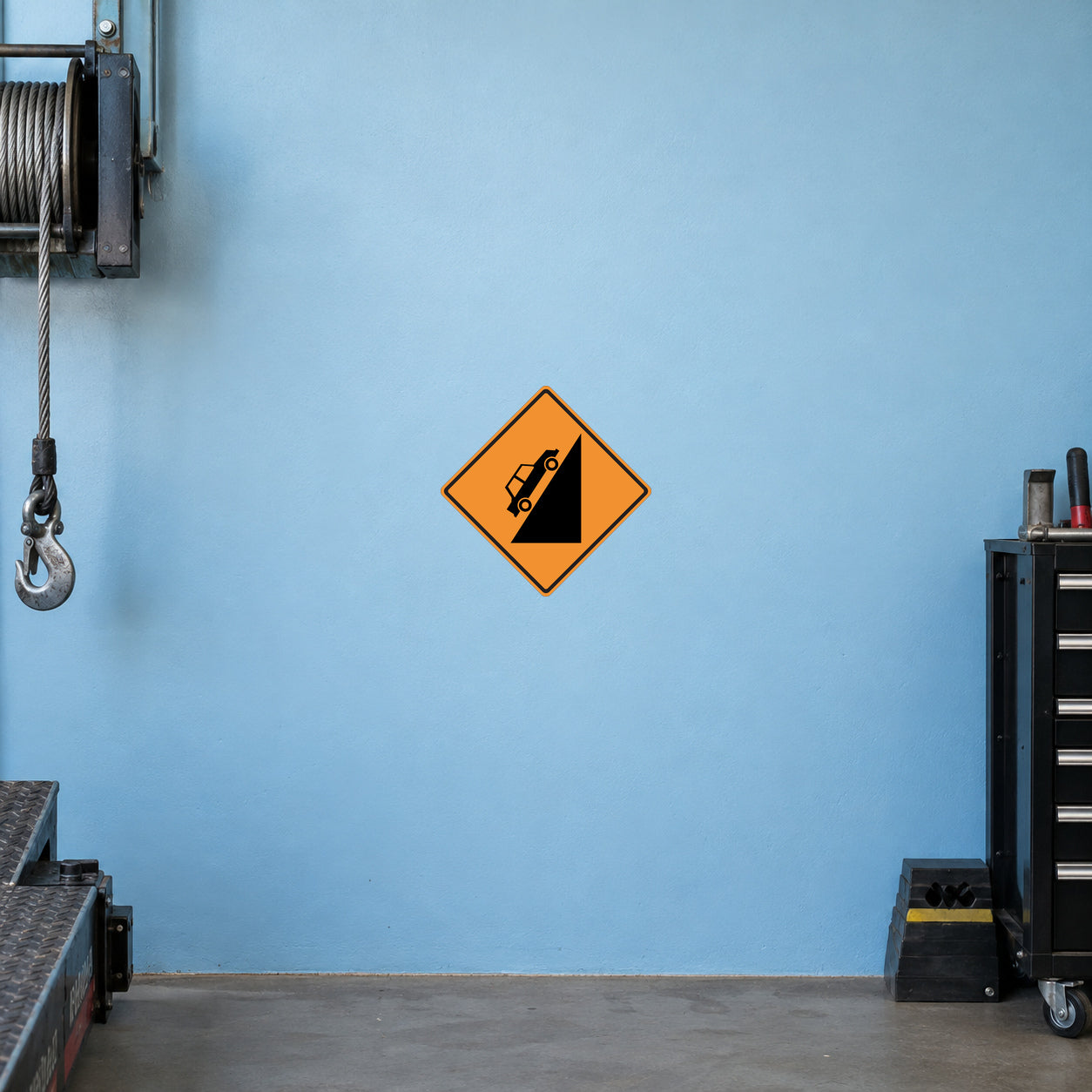 Road Sign Sticker applied in A rural vehicle recovery garage, uninterrupted pale blue painted wall, winch cable extreme left