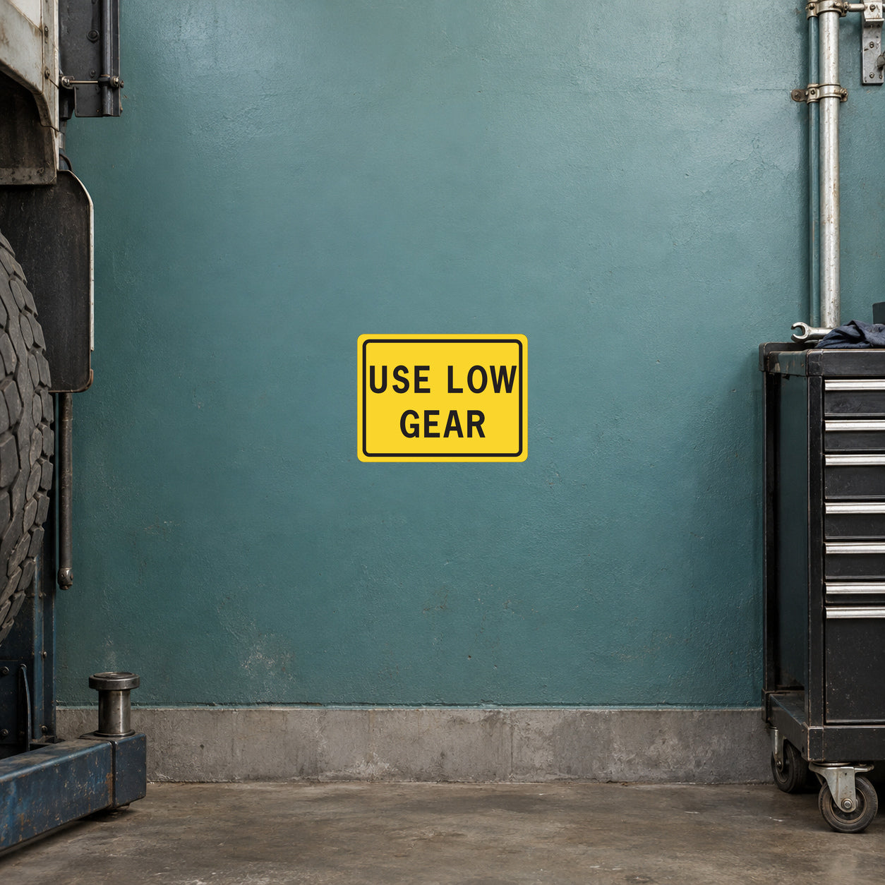 Road sign sticker: yellow rectangle with black text 'USE LOW GEAR'.