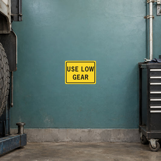 Road sign sticker: yellow rectangle with black text 'USE LOW GEAR'.